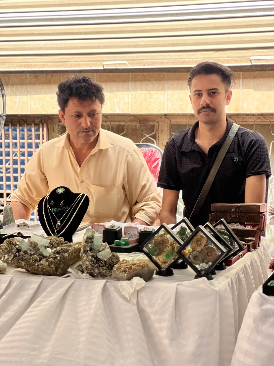 Raw gemstone clusters, jewelry and display boxes on a table at the Gems Bazaar