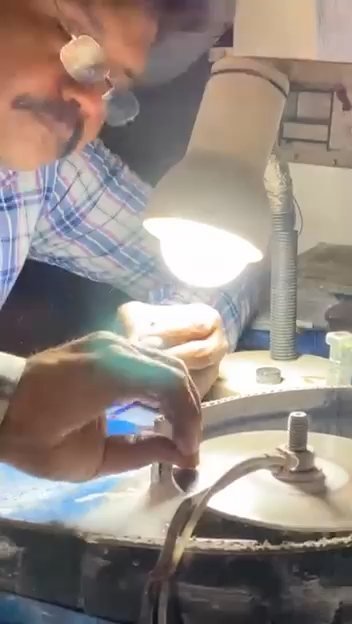 Craftsman faceting a gemstone on the cutting wheel at the workshop