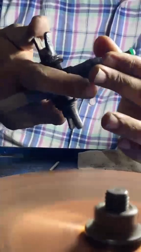 Close view of hands holding a cutting tool over a copper cutting wheel